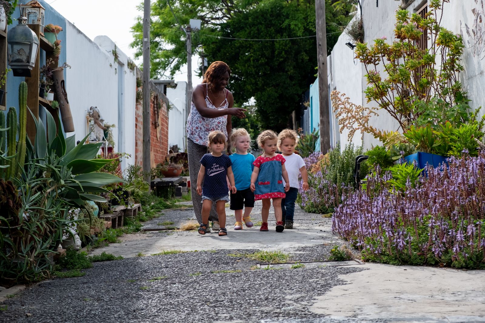 Teacher Ursula Bongongo with four toddlers walk through an alley, looking for butterflies. The toddlers are the members of the Active Baby Bilingual Playgroup, which Ursula ran for 2 years. 